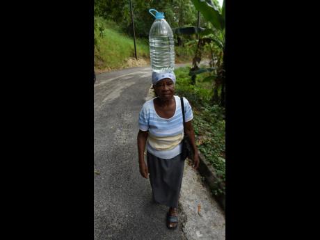 Emelyn Banton makes her way home after another of her daily trips to fetch water in Aberdeen square, St Elizabeth.