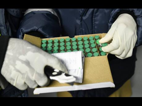 Credit: Ricardo Makyn Health officials inspect COVID-19 vaccines at the National Health Fund warehouse after they arrived on Monday.