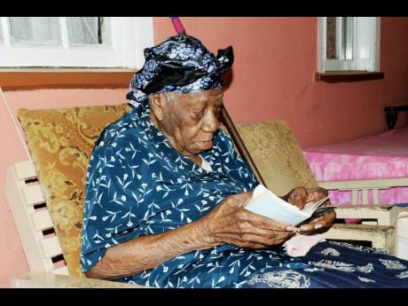 Credit: File In this 2010 photo, Violet Moss-Brown, who was 110 at the time, reads her ‘Daily Bread’ at her home in Duanvale, Trelawny.