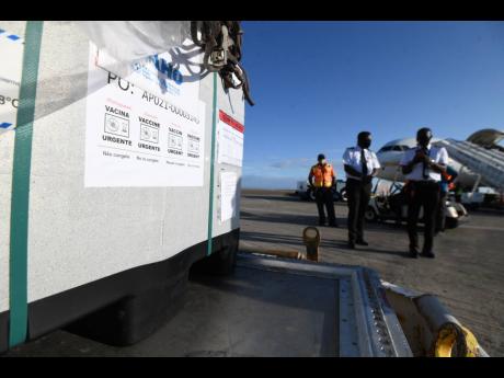 Pilots stand next to the cargo containing the COVID-19 vaccines at the Norman Manley International Airport. 