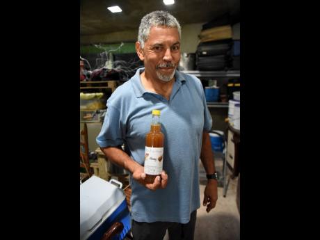 Credit: Ian Allen Spence holds a bottle of honey produced by his bees.