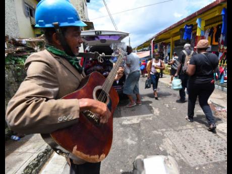 Roydell Edwards plays his guitar and sings outside the Brown’s Town market in St Ann.