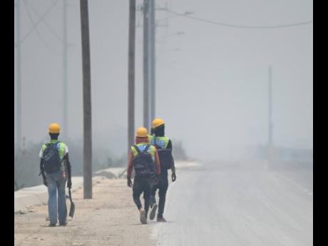 Workmen walk through think smoke that resulted from a fire at Riverton City Dump in Kingston in 2018.