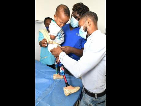 Credit: Rudolph Brown Orlando Brown (right) and Lasana Pryce, prosthetic technicians, fit four-year-old Mary with prosthetic legs.
