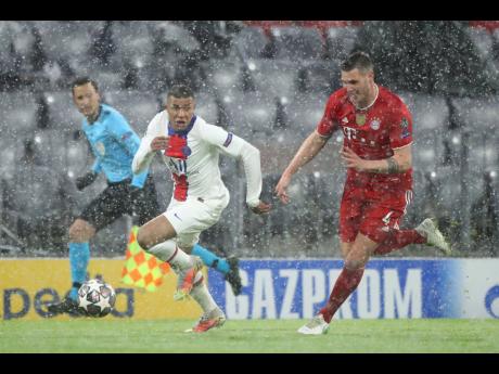 PSG’s Kylian Mbappe, left, controls the ball as Bayern’s Niklas Suele runs to stop him during the Champions League quarter-final match between Bayern Munich and Paris Saint Germain in Munich, Germany,  yesterday.