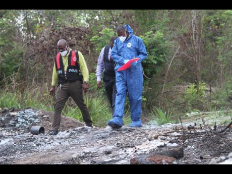 Investigators process the scene where the remains of a woman were found in bushes in Sandy Bay, Clarendon on Thursday.