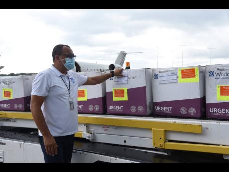Minister of Health and Wellness Dr Christopher Tufton looks at the 75,000 doses of AstraZeneca COVID vaccine shortly after they arrived in the island via chartered flight from Ghana on Thursday.