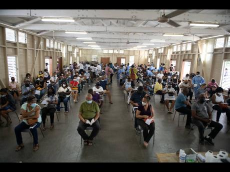 Scores of persons await their COVID-19 jab at the Mona Ageing and Wellness Centre in St Andrew on Sunday.