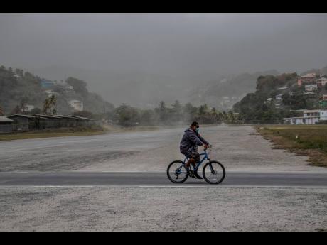 A man rides his bicycle past fields covered with volcanic ash a day after the La Soufriere volcano erupted, in Kingstown, on the eastern Caribbean island of St Vincent and the Grenadines last Saturday.