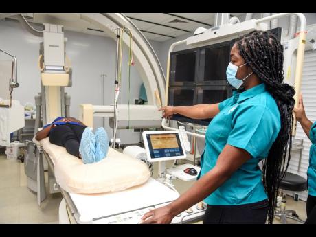 With the help of a colleague, Skyers shows the news team how the scanners work when they are used with patients.