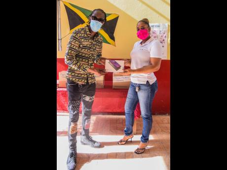 Dancehall legend Bounty Killer presents a tablet to Keisha Heslop-Pessoa, vice-principal of Seaview Gardens Primary School. The Bounty Foundation donated 40 of the devices to the school to assist children with online learning.