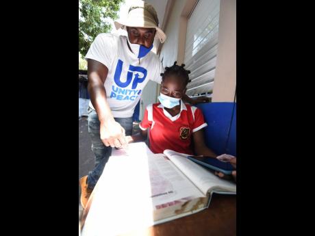 Credit: Ian Allen Alphanso Spencer helps Meloney Hinds, fourth form student at Kingston Technical High School, with her schoolwork.