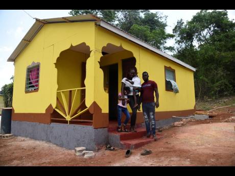 Lemaya Webb (right) with his family in front of their new home, built with the assistance of Nicholas Clarke, in the New Building area of St Elizabeth.