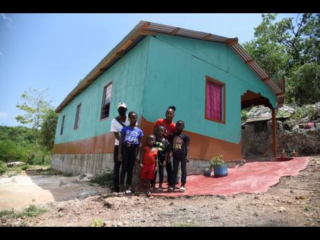 Nicholas Clarke (left) with Thericia Kelly and her family outside of their new home in New Building, St Elizabeth. Kelly said their former home was unsuitable for living.