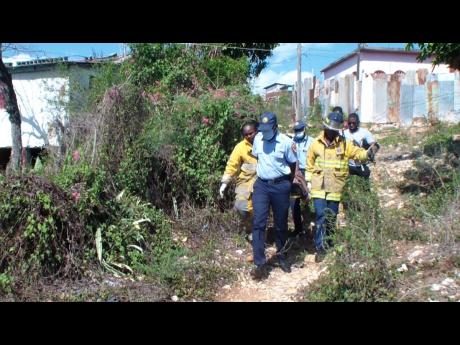 Rescuers transport a 66-year-old man from a hole where he was found in Jones Avenue, Spanish Town, St Catherine, yesterday.