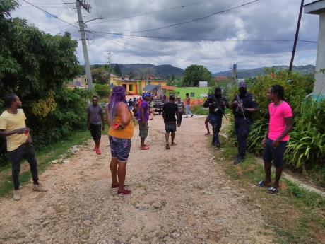 Police personnel stand guard outside Spicy Hill Farm in Trelawny, after the manager reportedly shot Kimorlay Forbes to death.