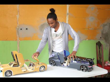 Oshane Dunstan shows off two miniature cars that he built.