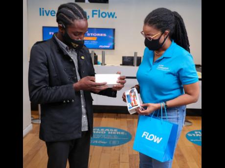 Oshane Dunstan (left) unboxes his new Flow smartphone after receiving it from Kayon Mitchell, director of communications, Flow Jamaica. 