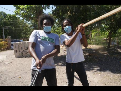 Entertainer Rawpa Crawpa (left) and Khacy ‘Official Boss’ Mohammed move around hardware material to the site of the new house.