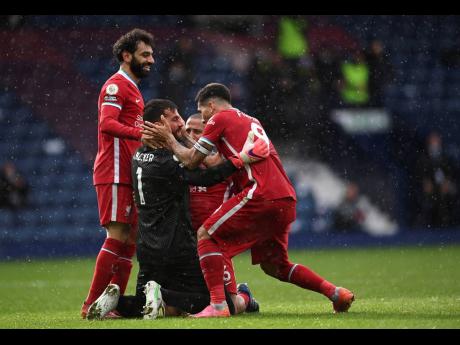 Liverpool’s goalkeeper Alisson (black top) celebrates with teammates after scoring his side’s second goal during the English Premier League match between West Bromwich Albion and Liverpool at the Hawthorns stadium in West Bromwich, England, yesterday. Liverpool won 2-1.