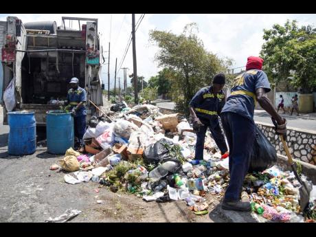 Garbage collectors tackle a massive pileup along Collie Smith Drive in Trench Town, St Andrew, on Sunday.