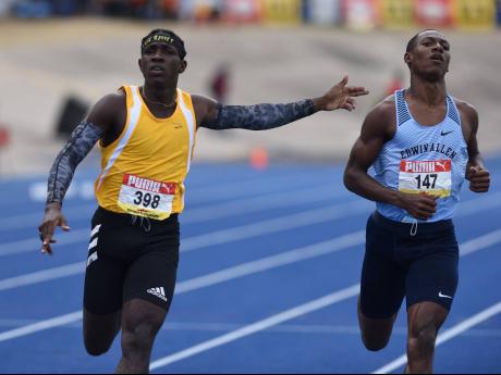 Petersfield High School’s Antonio Watson (left) celebrates with a gun play gesture towards Edwin Allen High School’s Bryan Levell as he crosses the finish line ahead of him in the Class One 200m final during the ISSA/GraceKennedy Boys and Girls’ Athletic Championships at the National Stadium on Saturday.