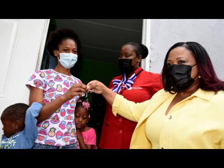 Member of Parliament for North Central St Catherine Natalie Neita (right) hands over the keys to a new home to Janell Mannings and her children. Looking on is Melanie Kelly, representative of First Union Credit Union.