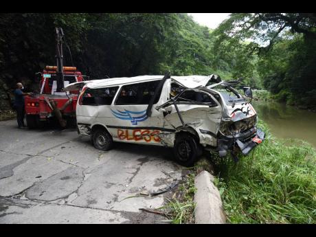 A wrecker lifts the minibus from the Rio Cobre after it was involved in an accident with a motor car along the Bog Walk Gorge yesterday in St Catherine.