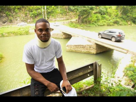 Jermaine Scott had a near-death encounter when his car ran off the road and fell into the Rio Cobre, pictured behind him. He was rescued by two divers, Dwayne ‘Lizard’ Stapelton and Rosaine ‘Chupsy’ McLaughin.
