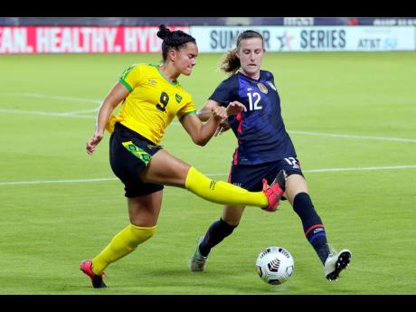 Jamaica forward Kayla McCoy (9) kicks the ball away from US defender Tierna Davidson (12) during the second half of their 2021 Summer Series on Sunday in Houston. The Americans won 4-0.