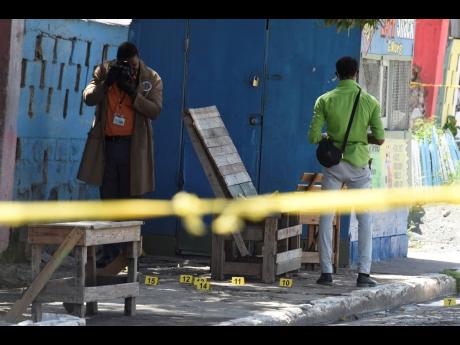Investigators process the crime scene in Third Street, Trench Town, St Andrew yesterday where Laphane Bent was shot and killed.