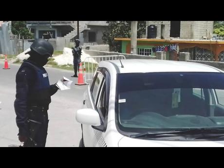 A member of the security forces checks the documents of this motorist.