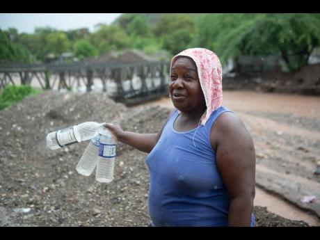 Corrol Jolly looks to fill these plastic bottles with water after two pipes in 11 Miles were damaged by flood waters.