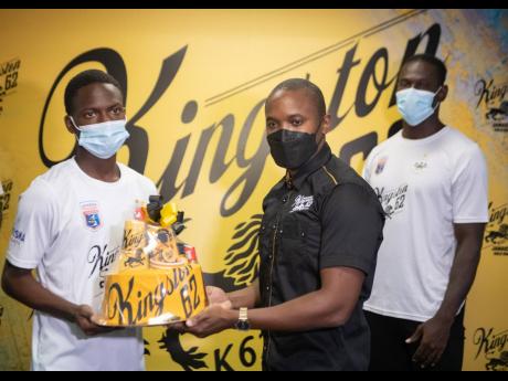 Cavalier’s Dwayne Atkinson (left) accepts a Kingston 62 gift package from Kamal Powell,  Regional Marketing Manager, J. Wray and Nephew Limited, at the Jamaica Football Federation head office in New Kingston yesterday. Looking on at right is Cavalier’s Kamoy Simpson.