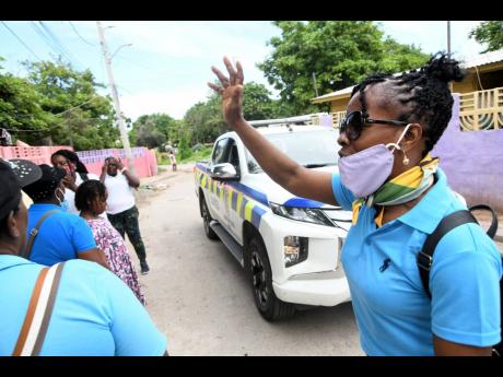 A woman prays on Monday for a family that came under a gun attack on Sunlight Street, Kingston 13, on Sunday. A baby was shot in the head.