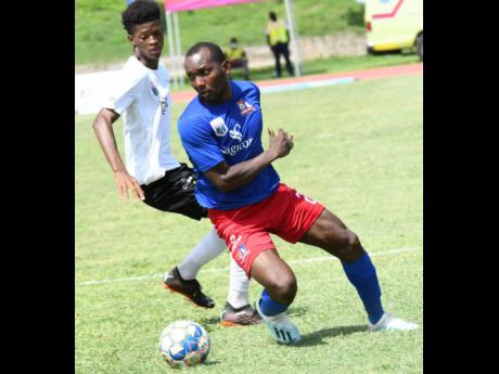 Dunbeholden’s Rondee Smith (right) turning away from Richard King of Cavalier during their Jamaica Premier League clash at the Stadium East field on Sunday. Dunbeholden won 1-0.