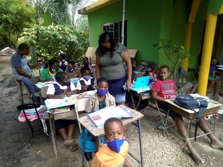 In this November 2020 photo, Garnet Foster and his wife, Camille, are seen helping children in Bullet Tree, Westmoreland, with schoolwork.