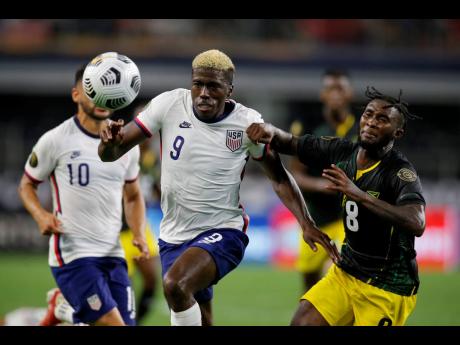 United States forward Gyasi Zardes (9) powering his way past Jamaica’s Oniel Fisher (8)  in the second half of last night’s Concacaf Gold Cup quarter-final  in Arlington, Texas. United States won 1-0. 