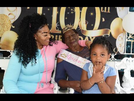 Charmaine Campbell (left) smiles as she looks at Mercella  Pearson during her 100th birthday celebration last Saturday, while Pearson’s great-granddaughter, Alaynah Anthony, looks on.