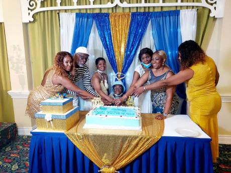 Ethlin Blake gets plenty of help to cut her birthday cake. Assisting are (from left) grandniece Nadine Hemmings-Gray, nephew Victor Abrahams, adopted daughter Dawnetta Seymour, niece Pauline Hemmings, and granddaughters Jennifer Hemmings and Winsome Hemmings-Thompson.