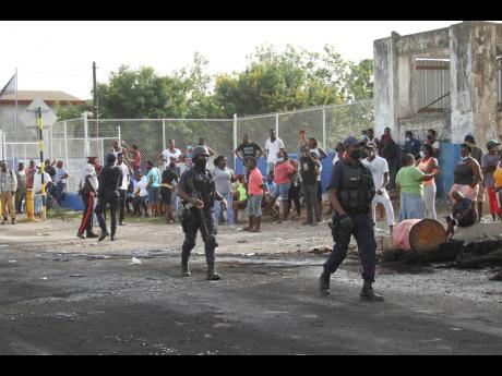 Police keep a close watch as residents of Top Hill, Hayes, Clarendon protested in front of the Hayes Police Station following allegations that the cops shot-up the car in which Kayanna was travelling with eight other persons.