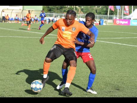 Credit: Kenyon Hemans Kemar Flemmings (left) of Tivoli Gardens FC shielding the ball from Dunbeholden’s Shakeen Powell during their Jamaica Premier League match at the UWI/Captain Horace Burrell Centre of Excellence yesterday. The match ended 1-1.