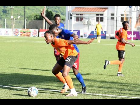 Earon Elliott  (front) of Tivoli Gardens shielding the ball from Dunbeholden’s Romario McPherson during their  Jamaica Premier League match at the UWI/Captain Horace Burrell Centre of Excellence on Monday. The match ended 1-1.