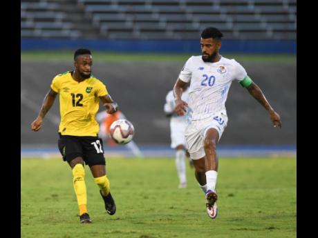 Jamaica's Junior Flemmings (left) plays the ball away while under pressure from Panama's Anibal Goday Lemus during Sunday night's Concacaf World Cup qualification match at the National Stadium. Panama won 3-0.