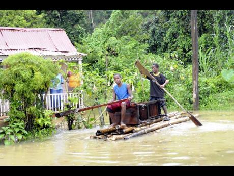 In this 2010 photo, two teen boys use a raft to traverse the floodwaters in their home community of Chigwell in Hanover.