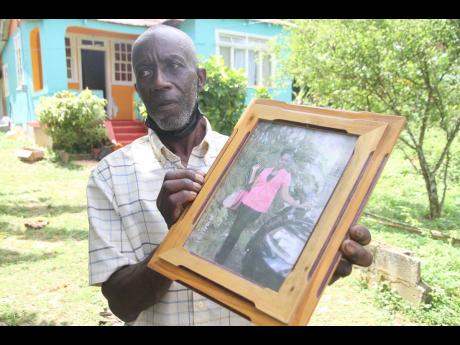 A distraught Ean Richards shows a photograph of his daughter, Annakaye Richards, who was murdered last Friday in her home in Comfort, Manchester.