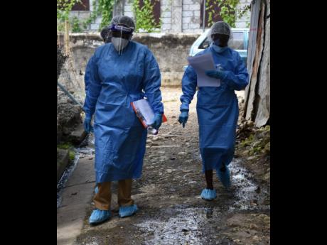 Community health aides walk through sections of Church Corner in Morant Bay , St Thomas, last August after the community was placed under quarantine to prevent the spread of COVID-19.