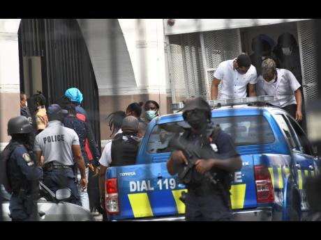 Some of the alleged 33 members of the Clansman Gang alight from a truck before entering the Home Circuit Court in downtown Kingston. 