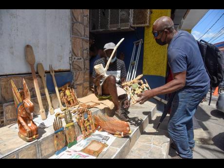 Danny Francis (right) seems interested in purchasing this replica of the Jamaican coat of arms from Benneth.