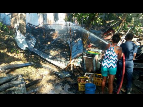 Residents of Combs Lane in Montego Bay, St James, gather outside what is left of their homes, which were destroyed by fire on Thursday afternoon.